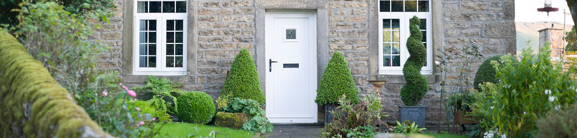 Decorative topiary trees in pots by front door
