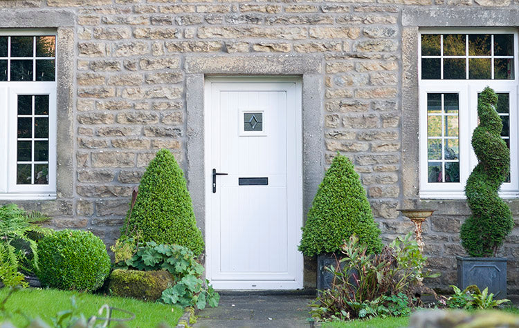 Decorative topiary trees in pots by front door